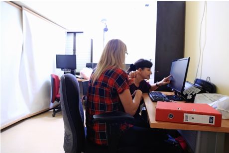 Teacher sitting next to a student working on a computer