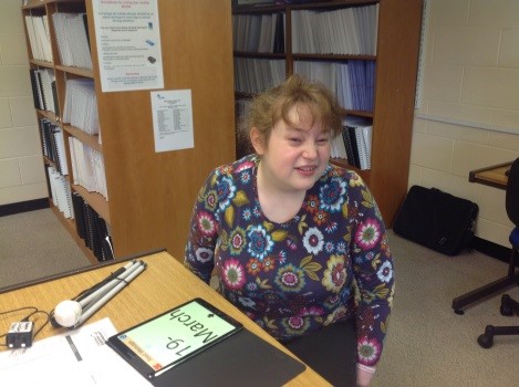 Erin sitting at a table with her iPad open on the table 