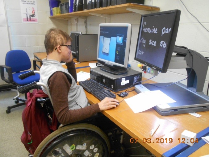 Jacob (Kuba) sitting in his wheelchair working at a computer