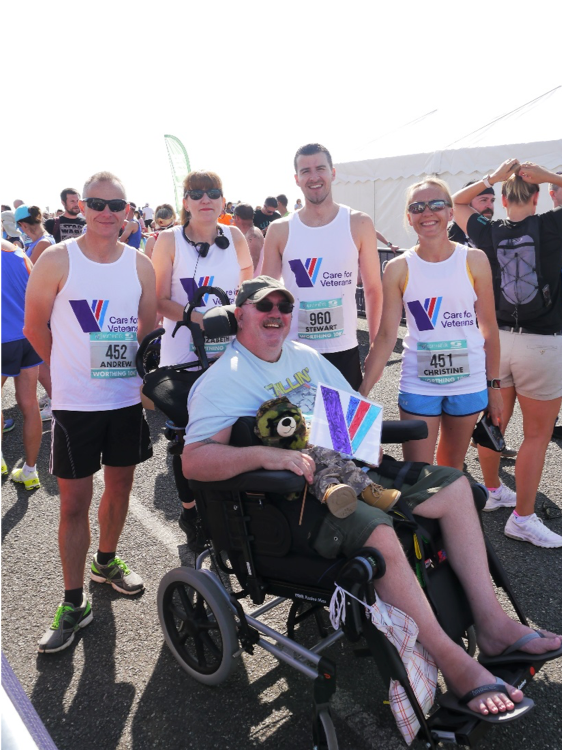 Tyron sitting in a wheelchair next to 4 runners from Care for Veterans