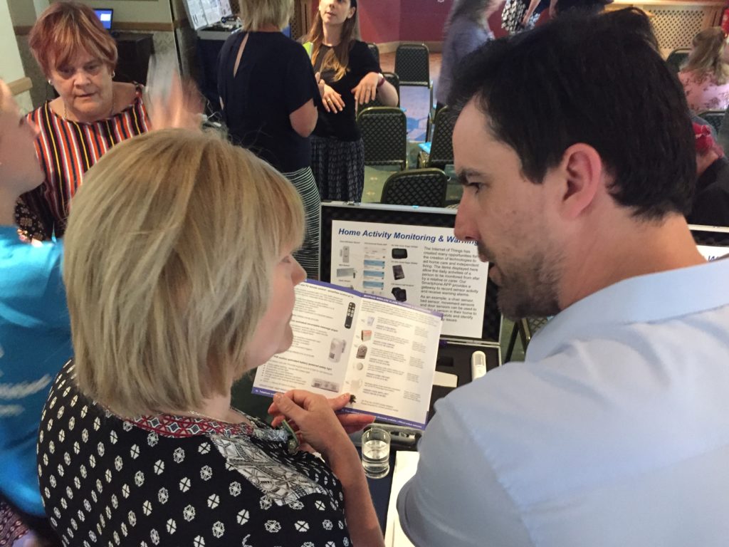 Lady and man looking at a book in an exhibition hall surrounded by assistive technology