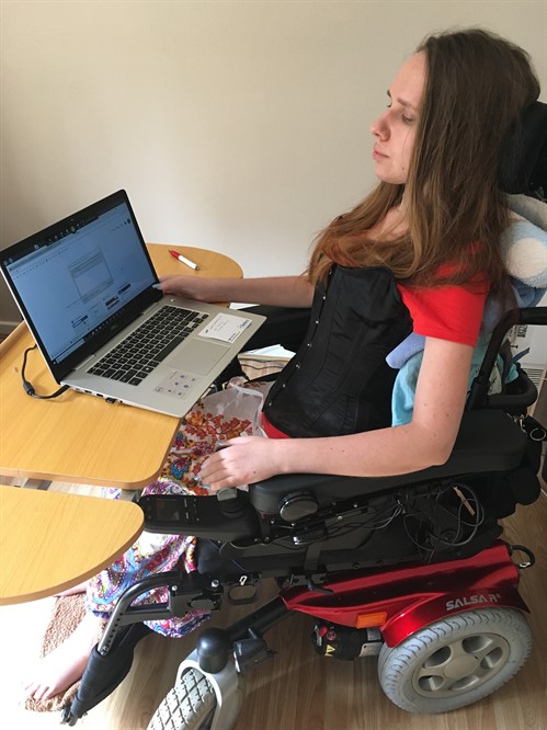 Dorota, a lady in an electric wheelchair sitting in front of a laptop computer 