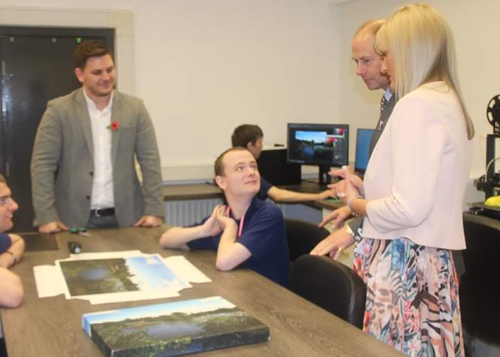 The earl of Wessex interacting with a student sitting at a desk in Lakeside Printing at The Hamlet