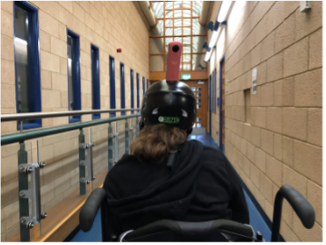 Student in wheelchair filming around College with a 360 camera mounted on a bike helmet