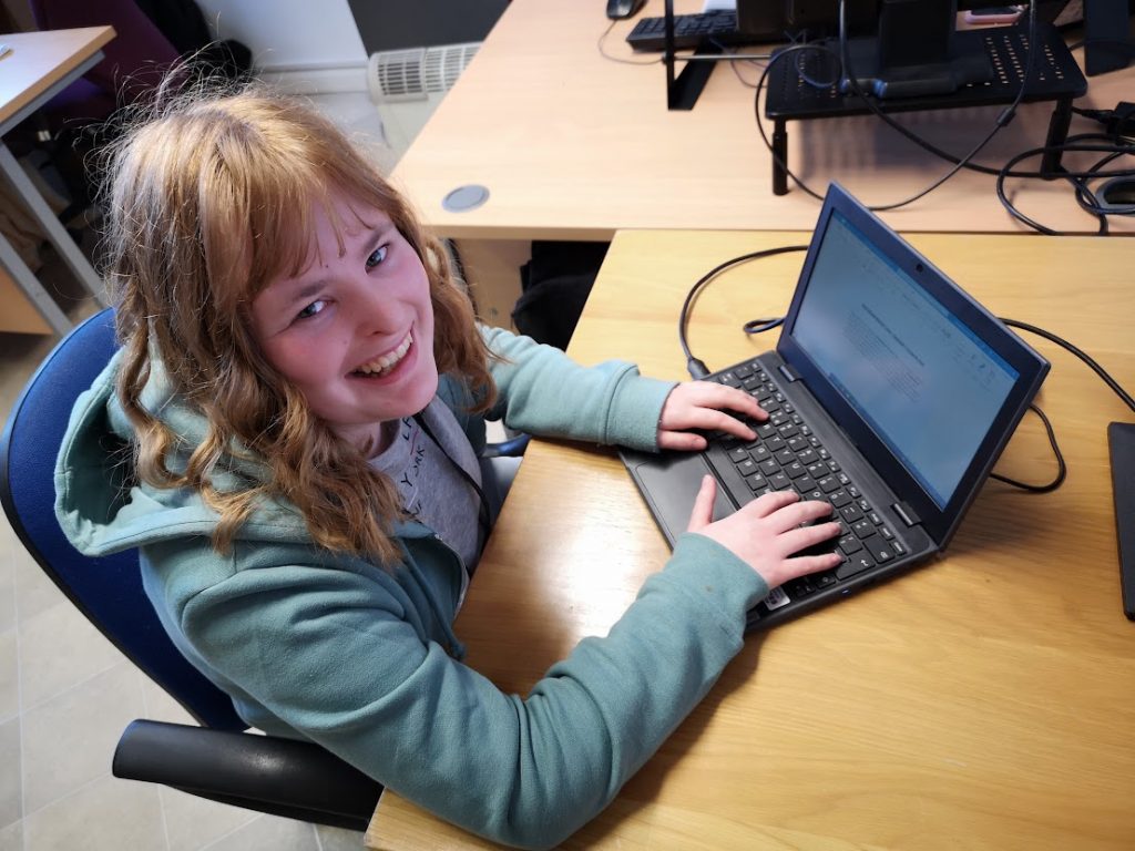 Student Finola sitting in front of a computer writing a blog post