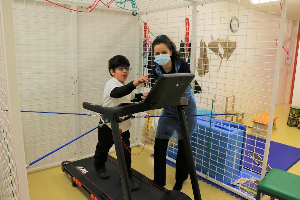 Youg boy walking on a tredmill during e physiotherapy session 