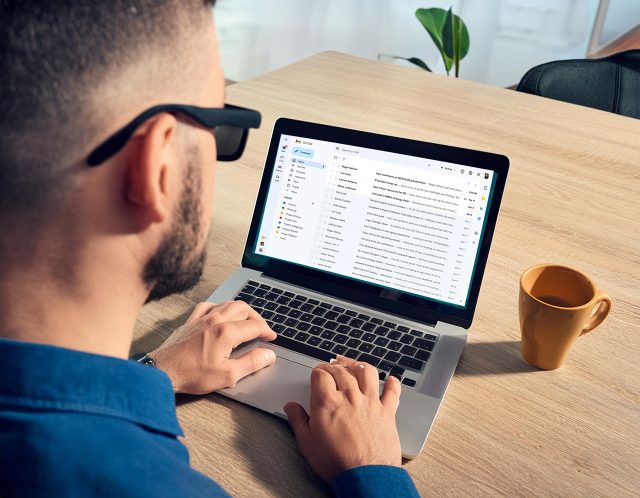 a visually impaired person sitting at a desk working on a laptop 
