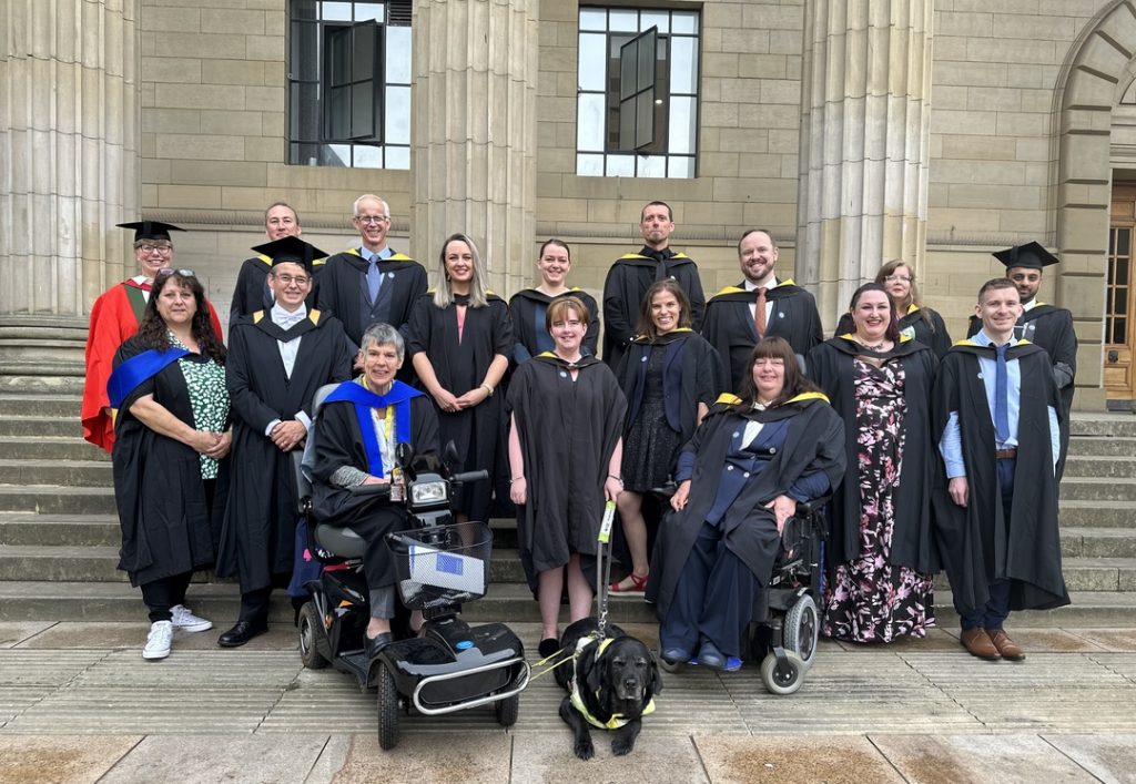 The first cohort of the Educational Assistive Technology course posed in graduation gowns on the Caird Hall steps
